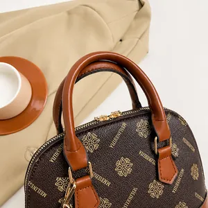 Nahaufnahme der braunen Retro-Tasche mit goldenem Muster und hochwertigem Tragegriff