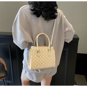 Detail of vintage beige crossbody bag with M-pattern print and slim shoulder strap