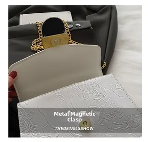 Dettaglio della chiusura magnetica e del motivo floreale goffrato sulla borsa bianca