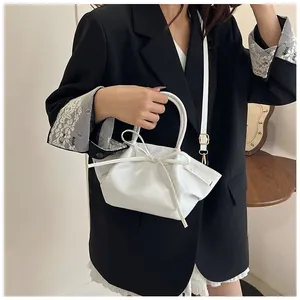 White bat-shaped handbag with decorative bow detail and elegant handle shown on model