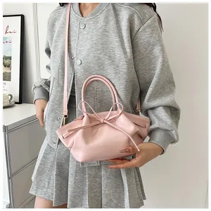 Detail of light pink pleated cloud bag featuring a sweet bow and adjustable strap