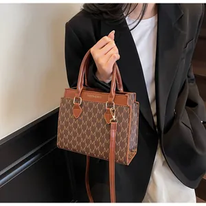 Detail of vintage brown monogram handbag worn with a chic black blazer and gold lettering