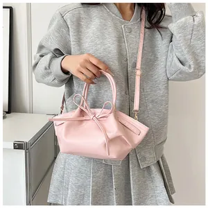 Detailed view of pink bow handbag featuring soft PU leather texture and adjustable strap