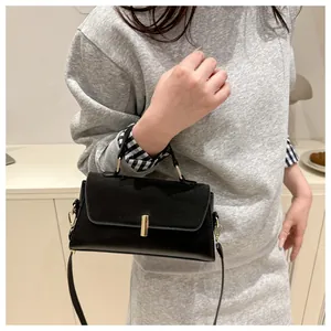 Détail du fermoir métallique et de la texture noire lisse du sac à bandoulière