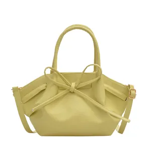 Yellow bucket bag with a 3D bow design, featuring top handles and an adjustable strap