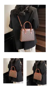 Close-up of vintage brown handbag with M-pattern print and adjustable leather strap