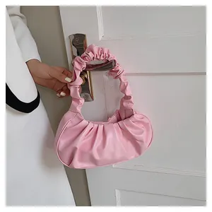 Detail einer sanft rosa gefalteten Cloud-Tasche an einem weißen Türgriff