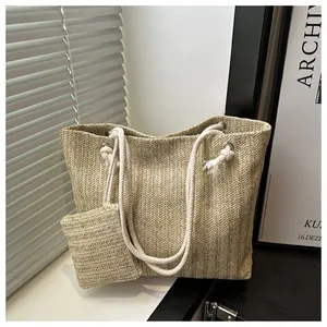 Close-up van de beige geweven shopper met visgraatpatroon en witte handgrepen van touw