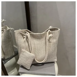 Detail van beige rieten draagtas met touwhandvatten en bijpassende muntenzakjesset