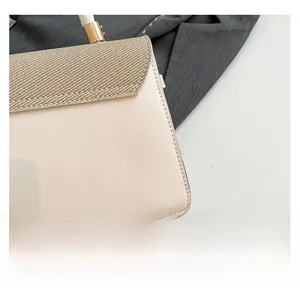 Detailed macro view showing beige leather texture and khaki woven fabric contrast on handbag