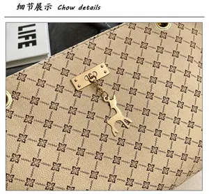 Detalle de bolso beige con estampado floral y colgante de ciervo dorado fino