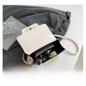 Detail of the open cream crossbody bag showing interior capacity and golden metal clasp