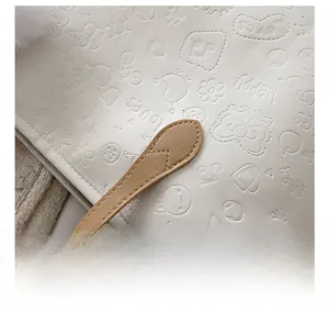 Détail du sac cabas blanc avec motifs gaufrés de dessins animés et bandoulière en cuir