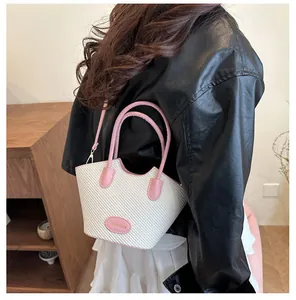 Detail der creme-gewebten Beuteltasche mit rosa Lederbesatz und verstellbarem Riemen