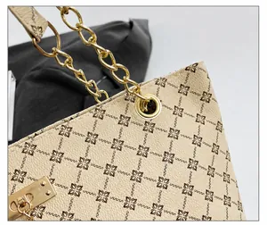 Detalle de cuero granulado crema con estampado de monograma y cadena de metal dorado bolso