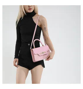 Pale pink shoulder bag featuring a golden bar lock and adjustable strap on a model