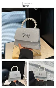 Detail einer silbernen Pailletten-Handtasche mit Metallschleife und Perlen-Tragegriff
