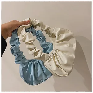 Nahaufnahme geraffter Halbmond-Schultertaschen in Hellblau und Cremeweiß aus weichem Kunstleder
