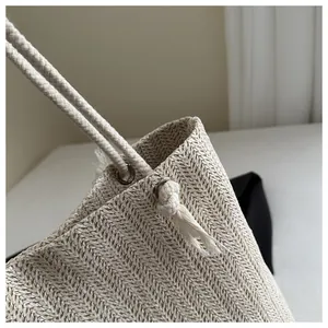 Detail van strooien tas met visgraatweefsel en geknoopte touwhandgreep aan metalen ring