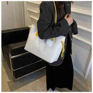 Détail du sac cabas blanc gaufré avec bandoulière jaune et pendentif boule en peluche