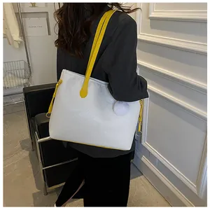 Détail du sac cabas blanc gaufré avec lanières jaunes et pompon blanc en fourrure douce