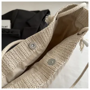 Detail van beige geweven strooien tas met magneetsluiting en katoenen koordgreep
