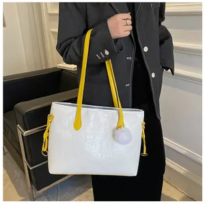 Détail du sac cabas blanc gaufré avec anses jaunes et accessoire pompon en peluche