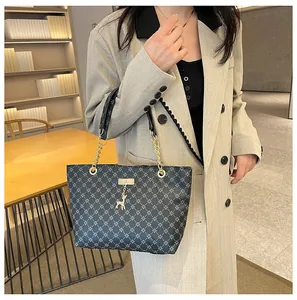 Detalle del bolso tote con monograma azul, herrajes dorados y un colgante de ciervo