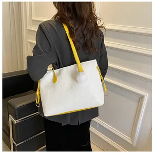 Détail d'un grand sac cabas blanc gaufré avec anses jaunes et pompon décoratif blanc