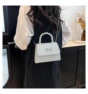 Silberne Pailletten-Mini-Tasche mit Perlengriff und Metallschleife am Modell