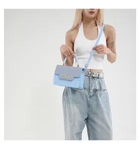 Detail of light blue crossbody bag with textured grey snake skin pattern flap and gold lock