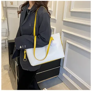 Détail du sac cabas en cuir gaufré blanc avec bandoulière jaune vif et pompon doux