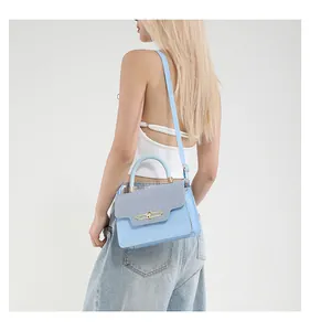 Close-up of a light blue leather bag with grey fabric flap and golden metal clasp details