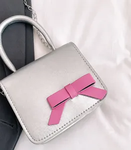 Détail macro du mini sac argenté avec un grand nœud rose et une chaîne en métal