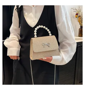 Detail der champagnergoldenen Pailletten-Handtasche mit Perlengriff und Silberbogen