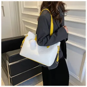 Gros plan d'un sac cabas blanc gaufré avec bandoulière jaune et détails en peluche