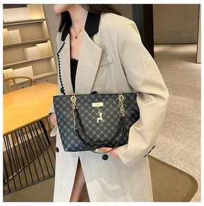 Detalle de bolso tote estampado con cadena dorada y colgante de ciervo elegante