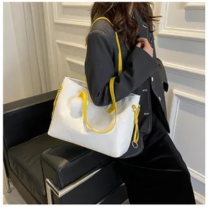 Gros plan du sac cabas blanc avec gaufrage cœur et bandoulières jaunes sur un mannequin