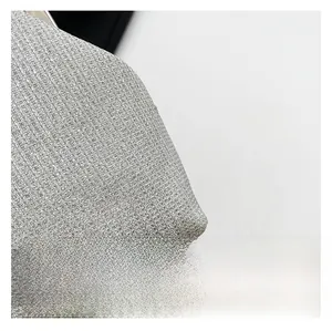 Detailed macro view of silver sequin fabric with metallic mesh texture and beaded chain