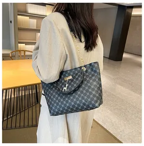 Detalle de bolso tote gris con patrón geométrico, cadena y colgante de ciervo plata