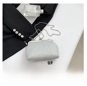 Detail of silver sequin evening bag with metal clasp and chain strap on desk