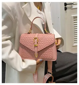 Detailed close-up of pink woven texture handbag with golden buckle and patterned strap