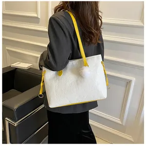 Détail du cabas blanc gaufré avec lanières jaunes contrastées et pompon décoratif