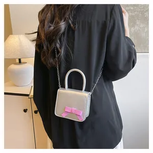 Mini sac bandoulière argenté avec nœud rose et chaîne en métal sur un mannequin