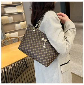 Detalle de bolso vintage con estampado de cruz, cadena metálica y colgante de ciervo