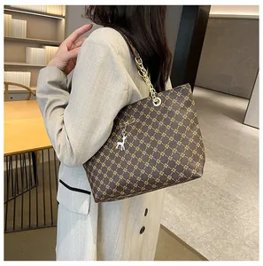 Primer plano de bolso tote vintage con estampado y correa de cadena dorada al hombro