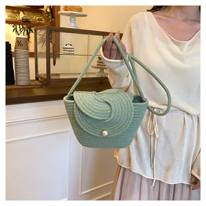 Detail of green handmade woven tote with unique swirl design and white pearl button closure