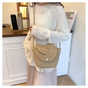 Detail of hand-woven crossbody bag featuring a large white pearl bead and spiral pattern