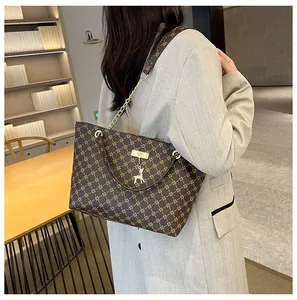 Detalle del bolso tote vintage con patrón de rejilla dorada y colgante de ciervo en el asa