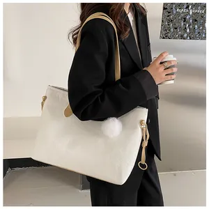 Détail d'un sac cabas blanc en similicuir gaufré avec pompon et anses de couleur marron